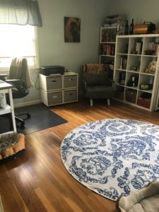 Photo of a home office with a rug, a bookshelf a chair and a desk.